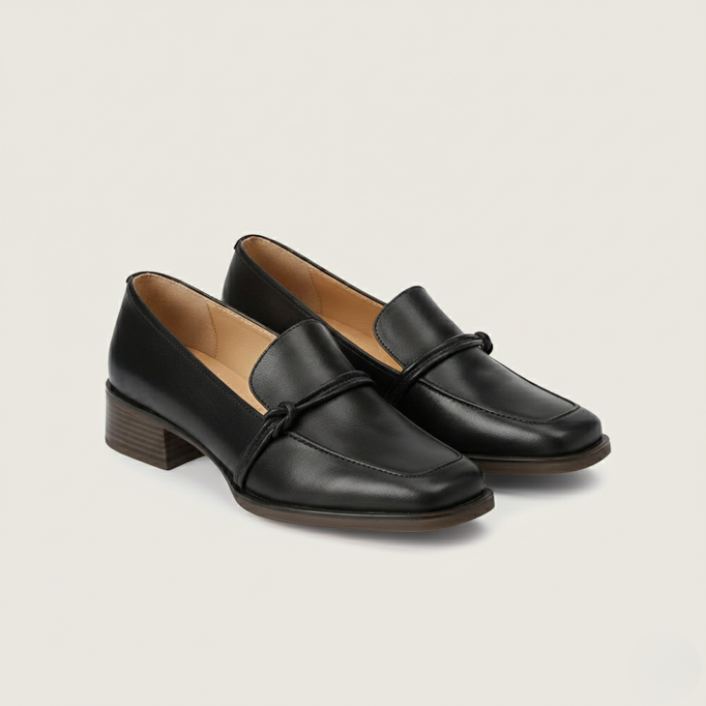 Pair of black loafers on a beige background