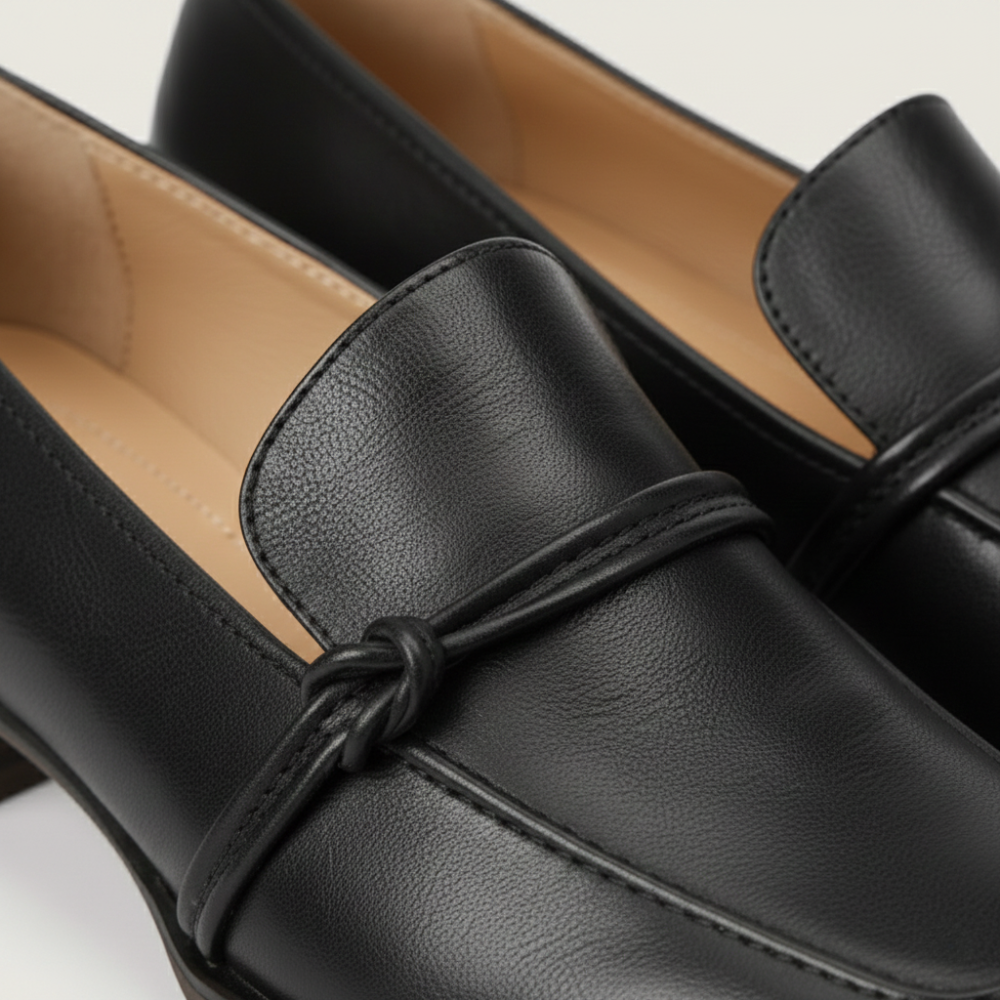 Close-up of a black leather loafer shoe for women with a bow detail.